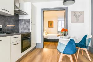 a kitchen and dining room with a table and blue chairs at Parking - Le Wild Forest - Centre Historique in Phalsbourg +16 photos