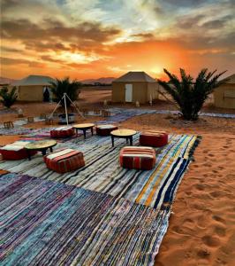 a group of tables and chairs on a rug in the desert at Krich Camp in Merzouga