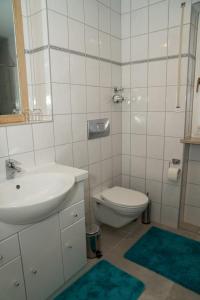 a white bathroom with a sink and a toilet at FeWo Waldi am Kurpark in Bad Tölz
