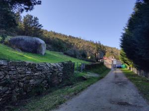 eine Steinmauer an der Seite einer Straße in der Unterkunft Albergue O Logoso in Campelo