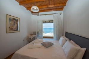 a bedroom with a bed with a view of the ocean at Frosos Beachfront Maisonette Acharavi in Acharavi