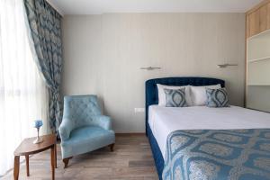 ein Schlafzimmer mit einem Bett und einem blauen Stuhl in der Unterkunft Helena Holiday B in Sweti Konstantin