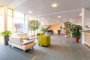 eine Bürolobby mit Sofas, Pflanzen und einem Klavier in der Unterkunft Hotel A1 Grauholz in Bern