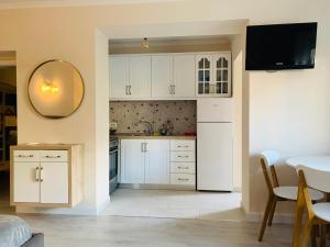 a kitchen with white cabinets and a mirror and a table at N&N Apartment in Përmet
