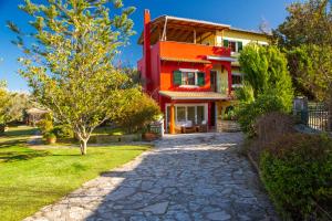 una casa rossa con un sentiero di fronte di Poly's Villa Lefkada a Città di Lefkada