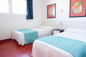 a hotel room with two beds and a window at Orquideas in Cala Galdana