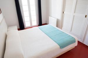 a white bed in a room with two windows at Orquideas in Cala Galdana