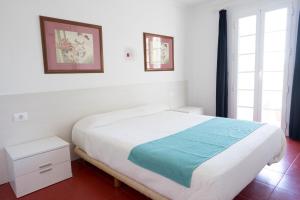 a white bedroom with a bed and two windows at Orquideas in Cala Galdana +22 photos