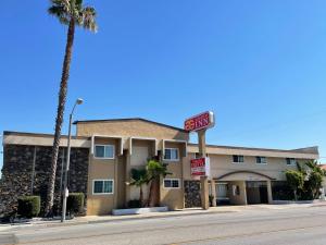 un hotel en una calle con una palmera en Grand Inn en Fullerton