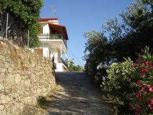 a road leading to a house with a stone wall at Paschos Rooms in Syvota