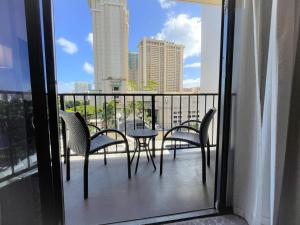 einen Balkon mit Stühlen und einem Tisch mit Stadtblick in der Unterkunft Aqua Palms 306 condo in Honolulu