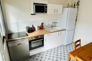a small kitchen with white cabinets and a refrigerator at Furnished Apartment With Balcony & Parking in A Secure Residence in Pessac