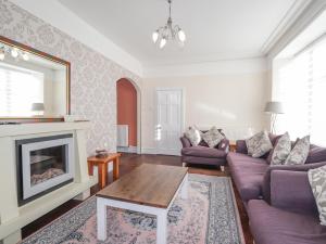 a living room with purple couches and a fireplace at 1 Seafield Street in Cullen