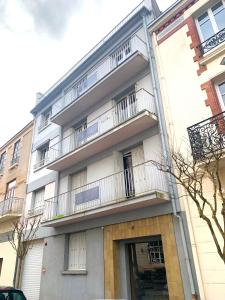 un immeuble d'appartements avec balcon sur le côté. dans l'établissement LE CALLOU - Parking - Face aux Thermes - Rez de Chaussée, à Vichy