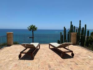 a patio with two chairs and a table and a fence at El jardin Botánico Villa LUZ in Altea