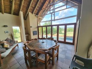 a dining room with a table and chairs and a large window at Thabanyani Mabalingwe in Bela-Bela