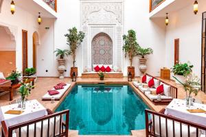 einem Pool in der Mitte eines Zimmers mit Tischen und Stühlen in der Unterkunft Riad Luciano Hotel and Spa in Marrakesch