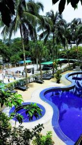 um resort com uma piscina com água azul e palmeiras em AGODA C VIEW @ Sri Sayang Beach Resort em Batu Ferringhi