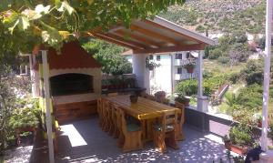 a patio with a wooden table and a fireplace at Studio Andric in Drvenik