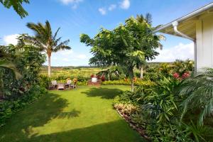 a garden with a lawn and trees and a house at The Lodge at Kukui’ula in Koloa