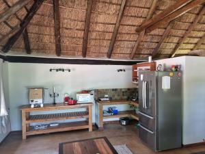 Il comprend une cuisine équipée d'un réfrigérateur et d'une table en bois. dans l'établissement Milkwood Cottage Mabalingwe, à Bela-Bela