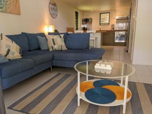 a living room with a blue couch and a glass table at Canopy 5 Chalet in Nelly Bay