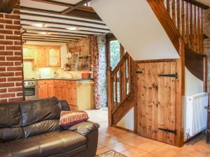 a living room with a couch and a kitchen at Swallow Cottage in Bucknell