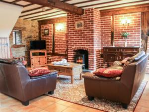 a living room with two chairs and a fireplace at Swallow Cottage in Bucknell