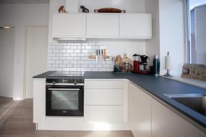 una cocina con armarios blancos y horno negro en New 2 Bedroom Apartment With Sea View en Tórshavn