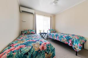 1 dormitorio con 2 camas y ventana en Charming CBD Apt 3bd 2bth - walk to Waterfront, en Darwin