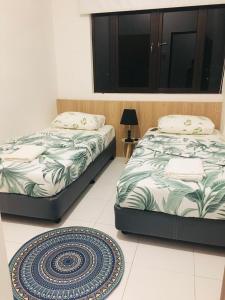 two beds in a room with a rug on the floor at Imperio Condostay Alor Star in Alor Setar