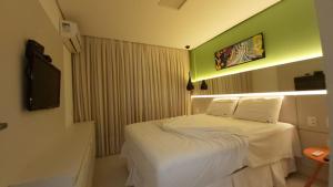 a hotel room with a bed and a tv at Bicalho Flat beira mar - Hotel PontaNegraBeach in Natal