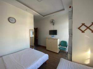 a bedroom with two beds and a desk and a clock at CSLTDL Minh Hùng in Da Lat