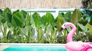 um flamingo rosa ao lado de uma piscina com plantas em Villa Beji Ayu em Seminyak