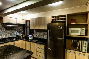 een keuken met een zwarte koelkast en een magnetron bij Apartamento Completo de 3 quartos em Gramado 2 in Gramado