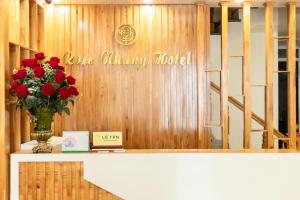 a vase of red roses on a counter with a sign at Cat Ba Rose Nhung Hotel in Cat Ba