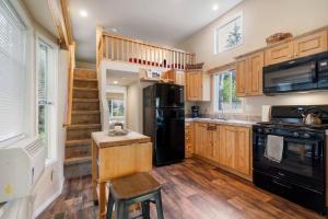 cocina con nevera negra y armarios de madera en New Tiny Home Steps Away From Mt. Rainier, en Ashford