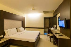 a hotel room with a bed and a television at Hotel Crescent Crest Sriperumbudur in Sriperumbudur