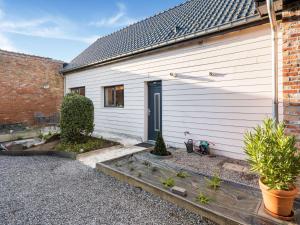 un bâtiment blanc avec une porte et quelques plantes dans l'établissement Restful Holiday home in Herselt with Garden, à Herselt