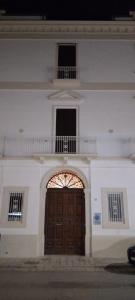 a large white building with a wooden door and a balcony at Dimora Erminia in Polignano a Mare