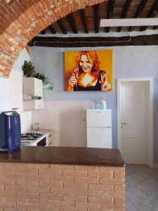 una cocina con una pintura de una mujer en la pared en La grotta nel borgo, en Roccastrada