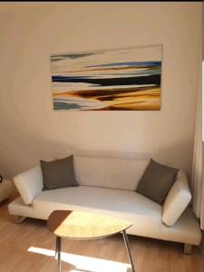 ein Wohnzimmer mit einem Sofa und einem Gemälde an der Wand in der Unterkunft Perfect apartment to visit the fair or city in Düsseldorf
