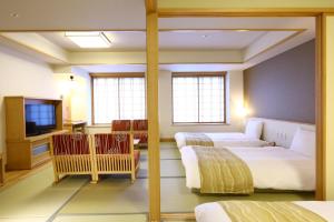 a hotel room with two beds and a television at Oyado Tsukiyo no Usagi in Izumo