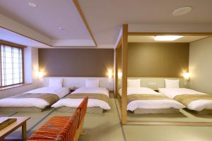 a room with four beds and a mirror at Oyado Tsukiyo no Usagi in Izumo