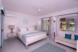 a white bedroom with a bed and a couch at Le Mandala Moris in Pointe aux Canonniers