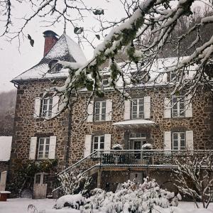 a large stone house with snow on it at La Demeure de Cyr in Saint-Chamant