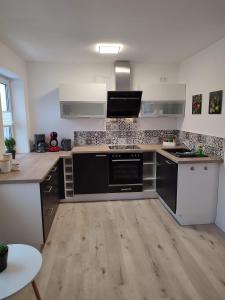 eine Küche mit schwarzen und weißen Geräten und Holzböden in der Unterkunft FeWo ERZ-Zeit in Annaberg-Buchholz