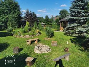 ogród z ławkami i miejscem na ognisko w trawie w obiekcie Bieszczady Noclegi "Muzyczna Chata" w mieście Olszanica