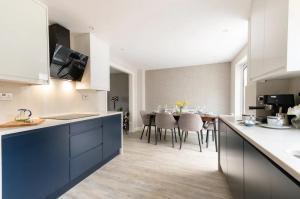 a kitchen with white cabinets and a dining room at Virginia Water Family getaway in Virginia Water