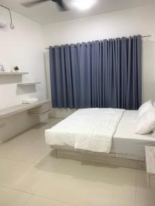 a bedroom with a bed and a blue curtain at 4A Icon Residence in Kuala Terengganu